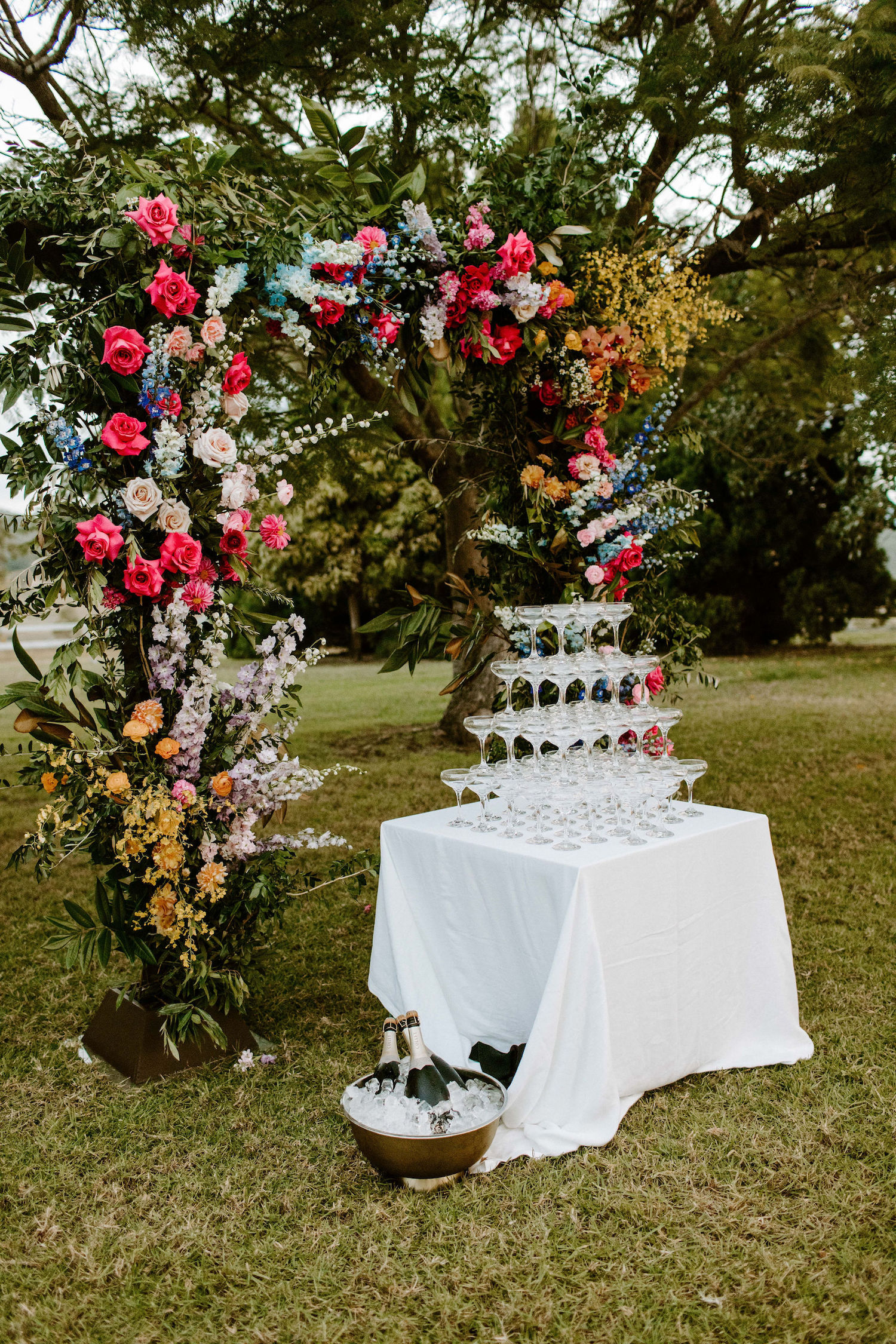 Vibrant floral arbour repurposed for this champagne tower garden party wedding